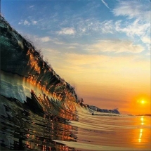 Stunning photo of the sunset reflecting of a glassy wave - Surfing