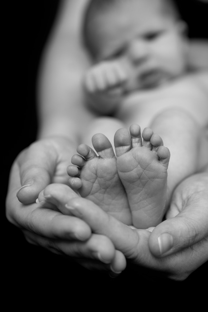 Baby resting in arms with feet in hands [photo]