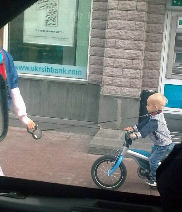 Child taken for a bike ride with dog collar and leash