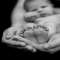 Baby resting in arms with feet in hands [photo]